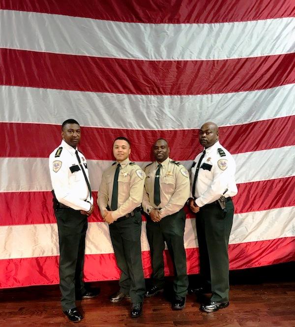 Lincoln Wilson standing with fellow officers in front of the USA Flag.