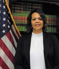 Carolyn Gordon poses for photo in front of book case with American flag