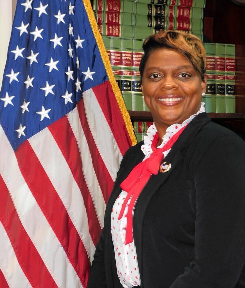 Shontina Reed poses with bookshelf next to American flag