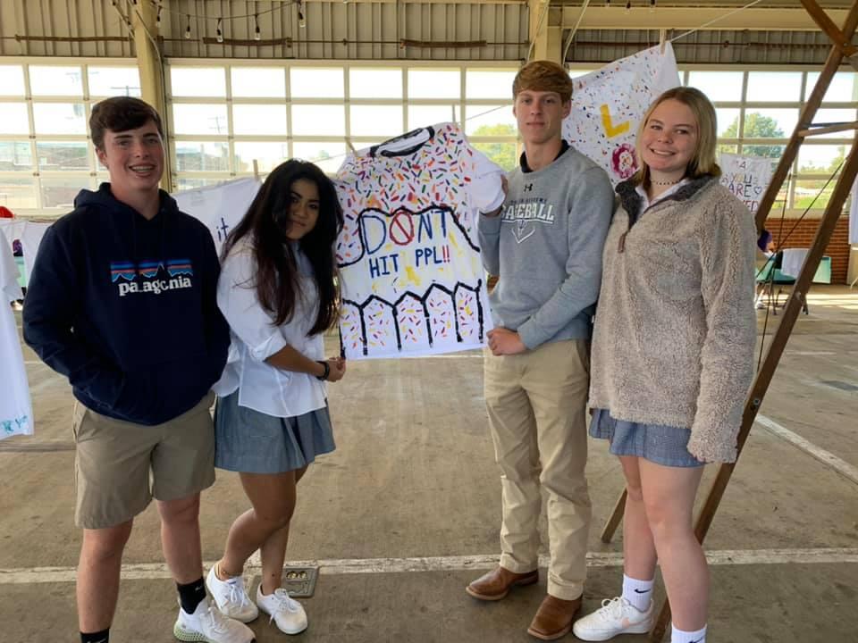 Student volunteers pose with shirt they painted.