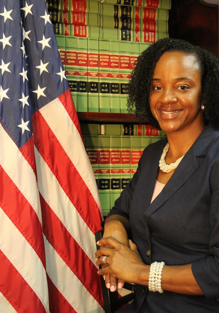 Sharon Donner posing for photo in front of book case with American Flag